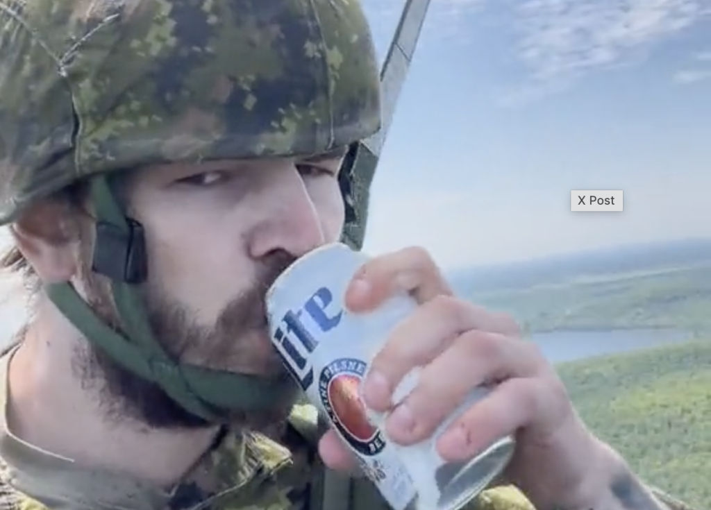 Canadian paratrooper in uniform drinking a beer.