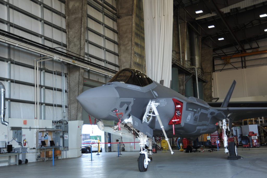 An F-35 fighter jet is parked indoors.