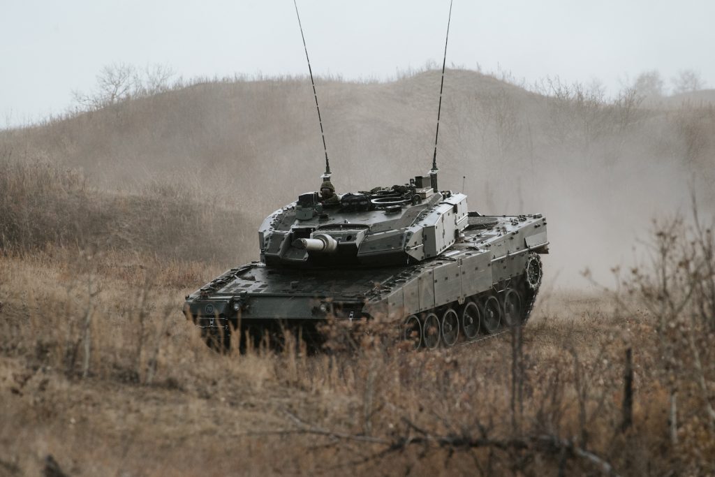 A Leopard tank travels on a grassy field
