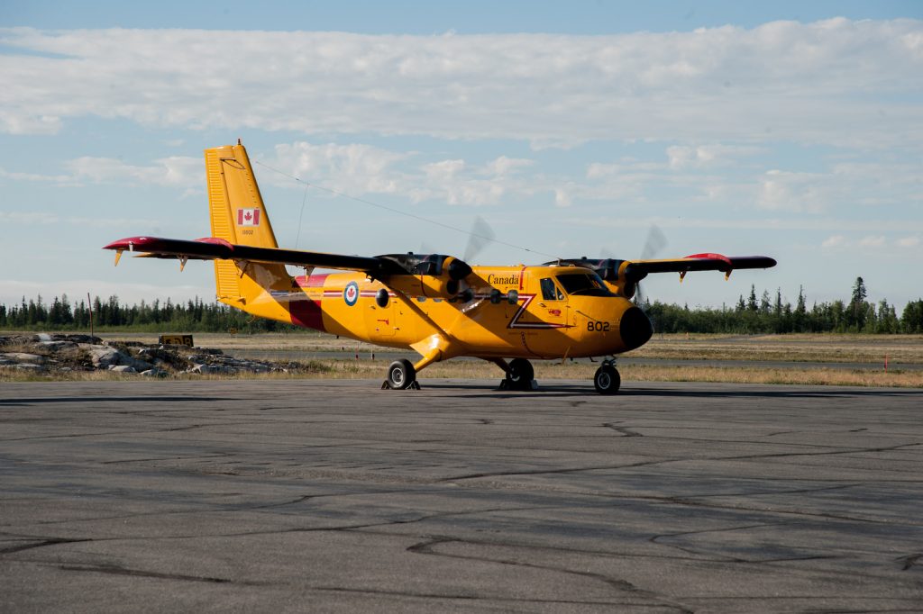 twin otter aircraft sits on the tarmac under mostly sunny skies