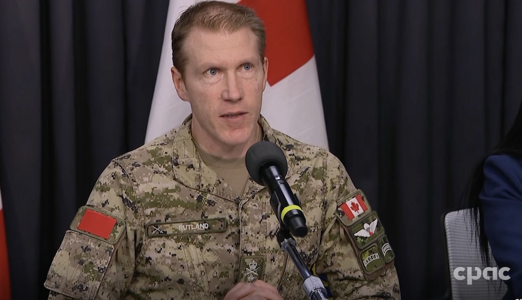 A screenshot taken from a computer of the news conference during which Maj. Gen. Wade Rutland responded to reporters’ question. The major general is wearing military garb and stands in front of a microphone.